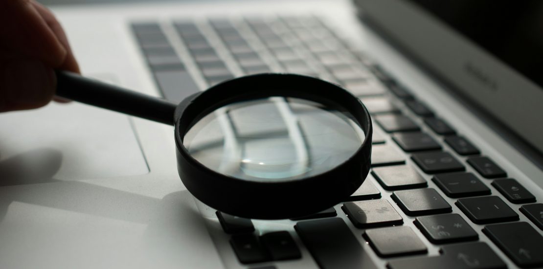 magnifying glass near gray laptop computer